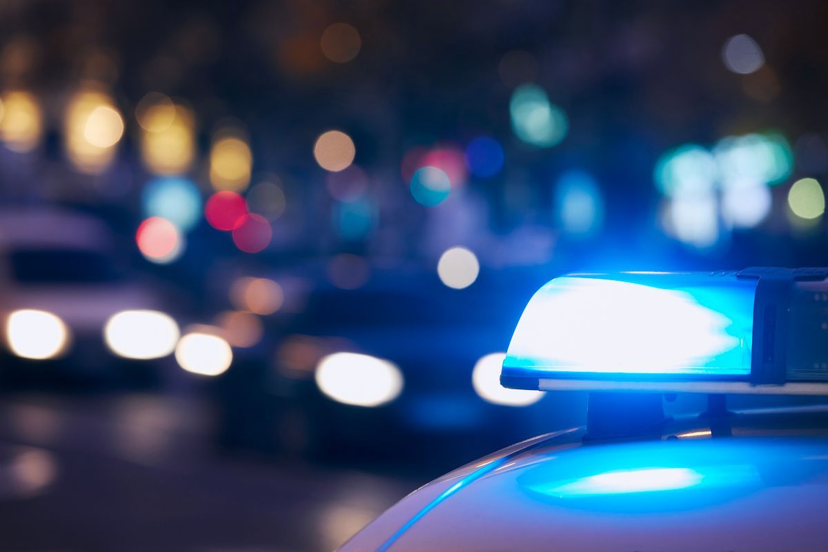 Flashing blue police light on a car at night with blurred city lights in the background