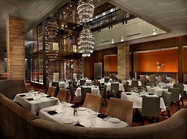 Elegant restaurant dining room with white tablecloths, chandeliers, and warm ambient lighting