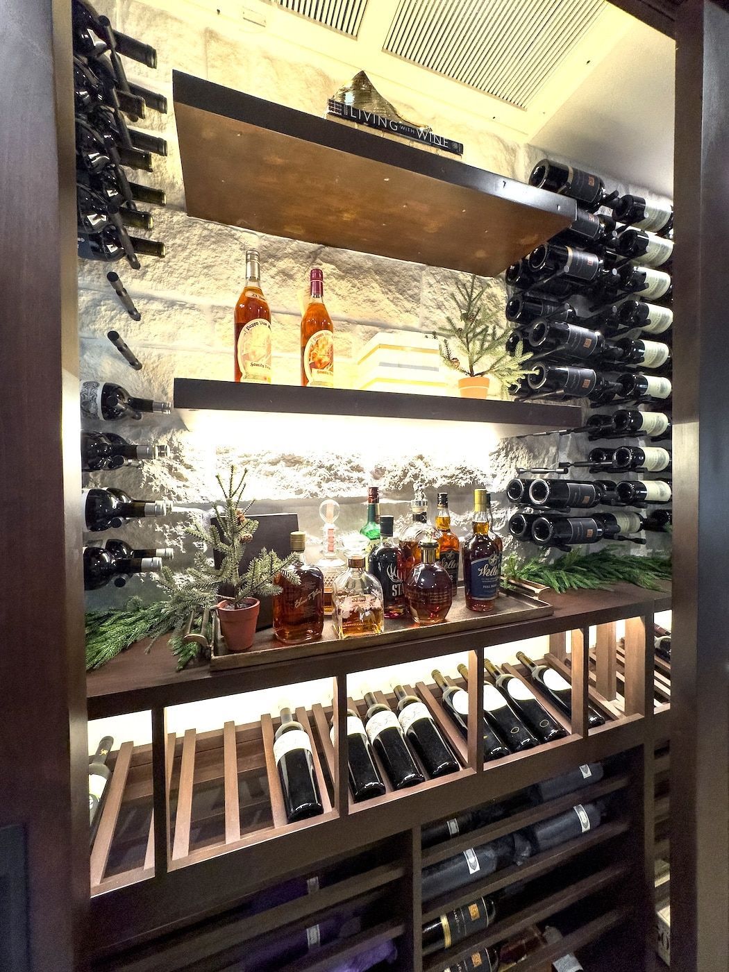 Stylish wine display with bottles on shelves, backlit bottles, and stacked wine racks in a wood-and-stone wall