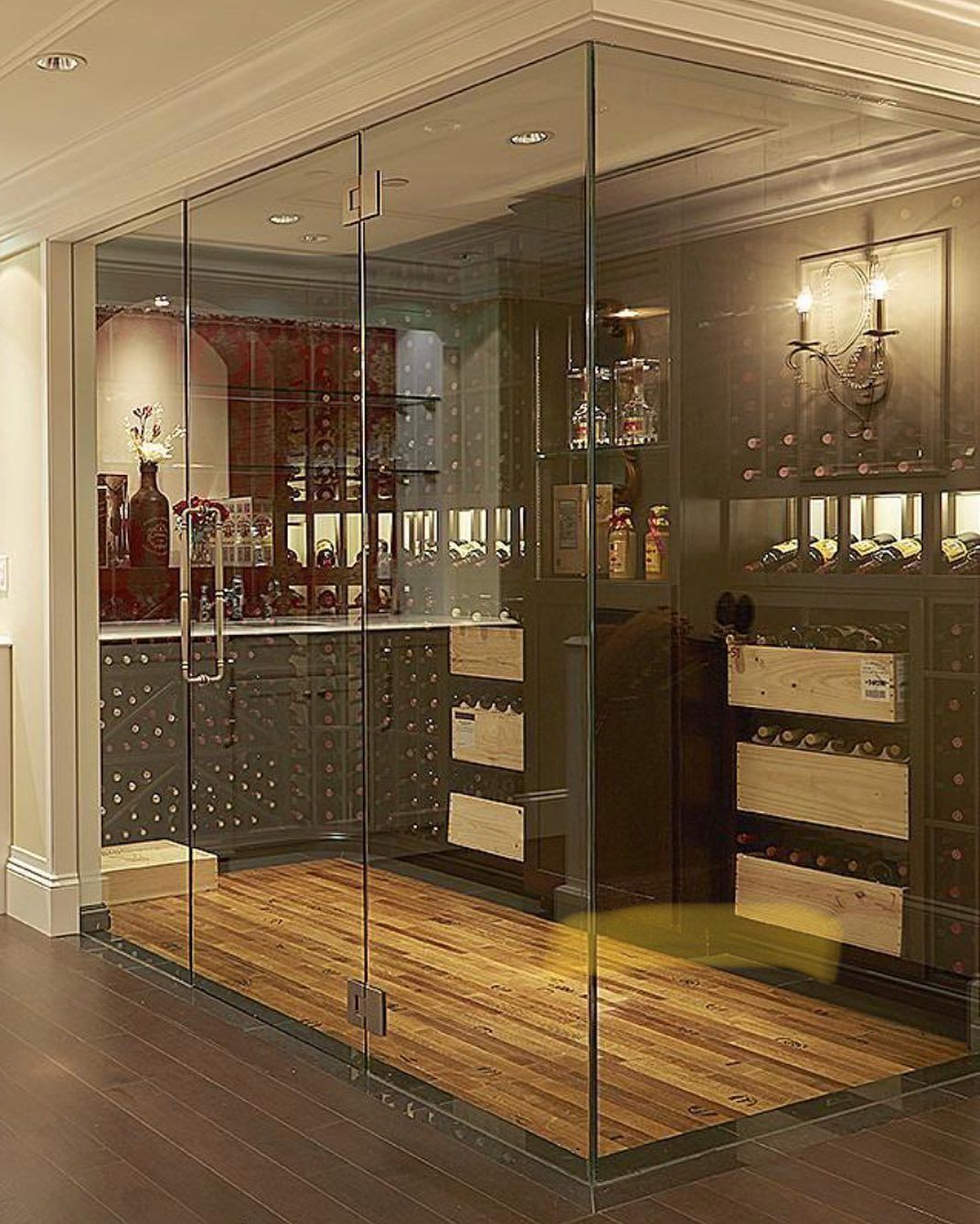 Glass-walled wine cellar with wooden floor and built-in wine racks inside a dining room