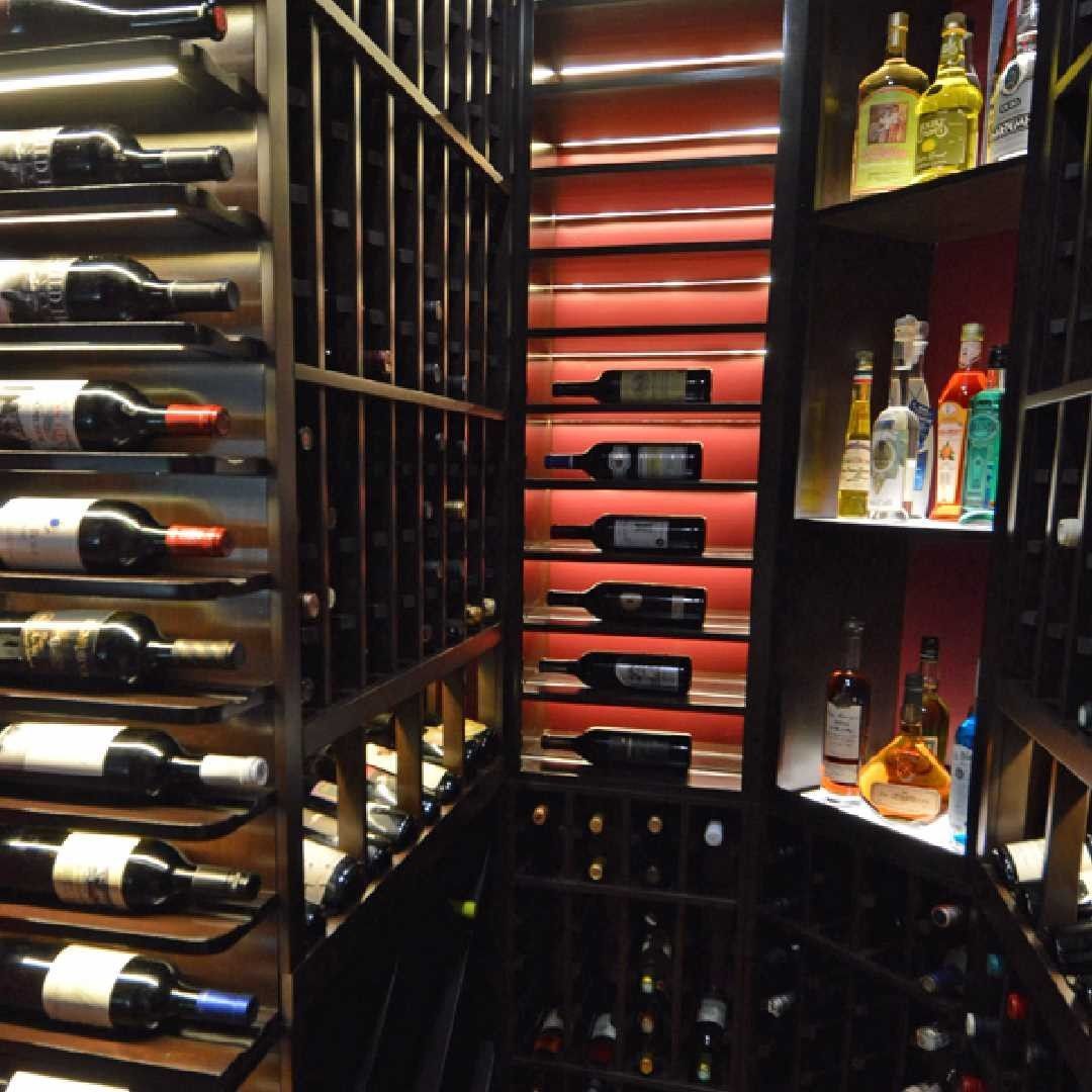 Wine cellar with racks of bottles on both sides and a black round table in the center