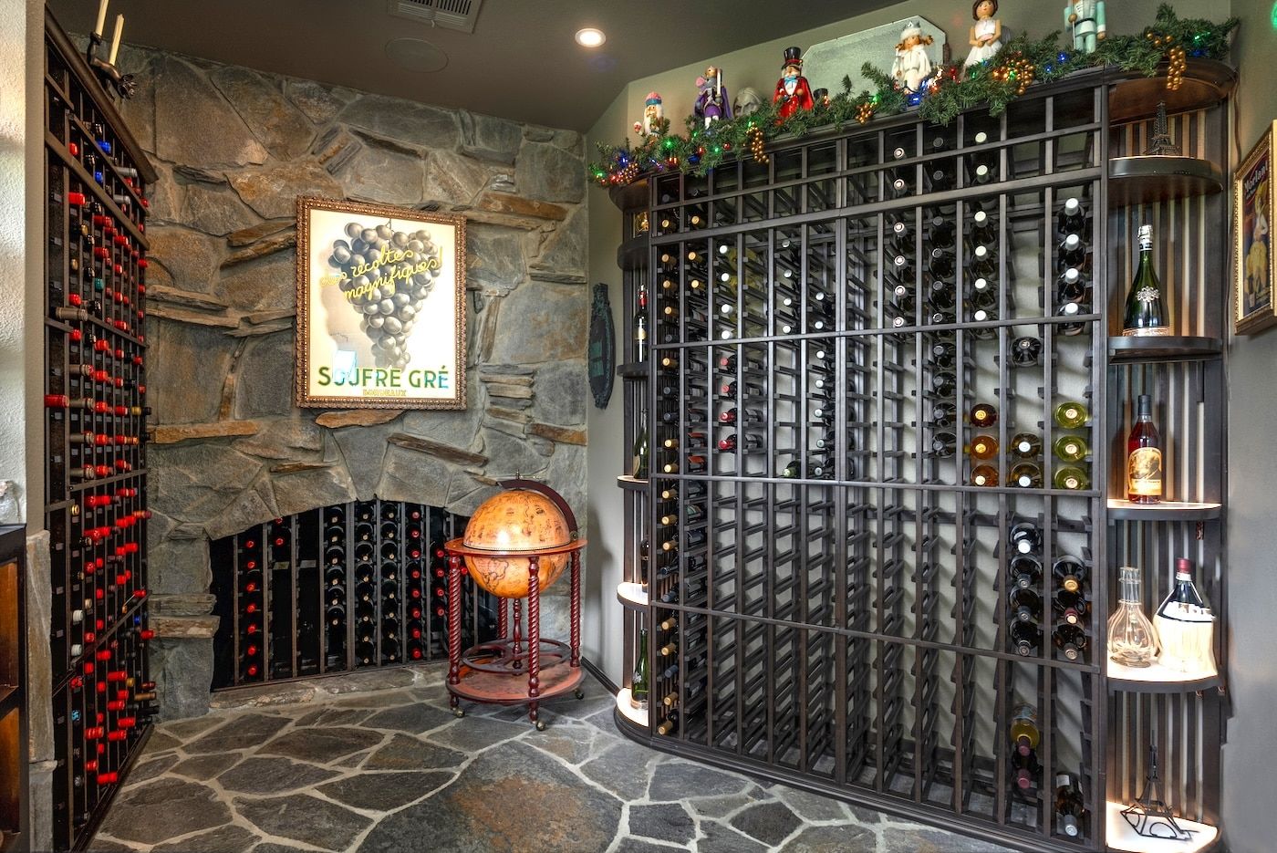 Stone wine cellar with wall-to-wall racks, a small fireplace, and festive garland decor