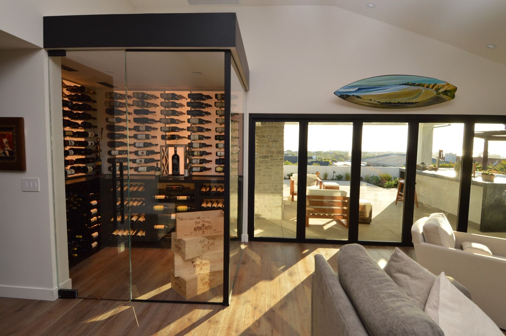 Modern living room with wine storage, ocean view through glass doors, and a beige sofa