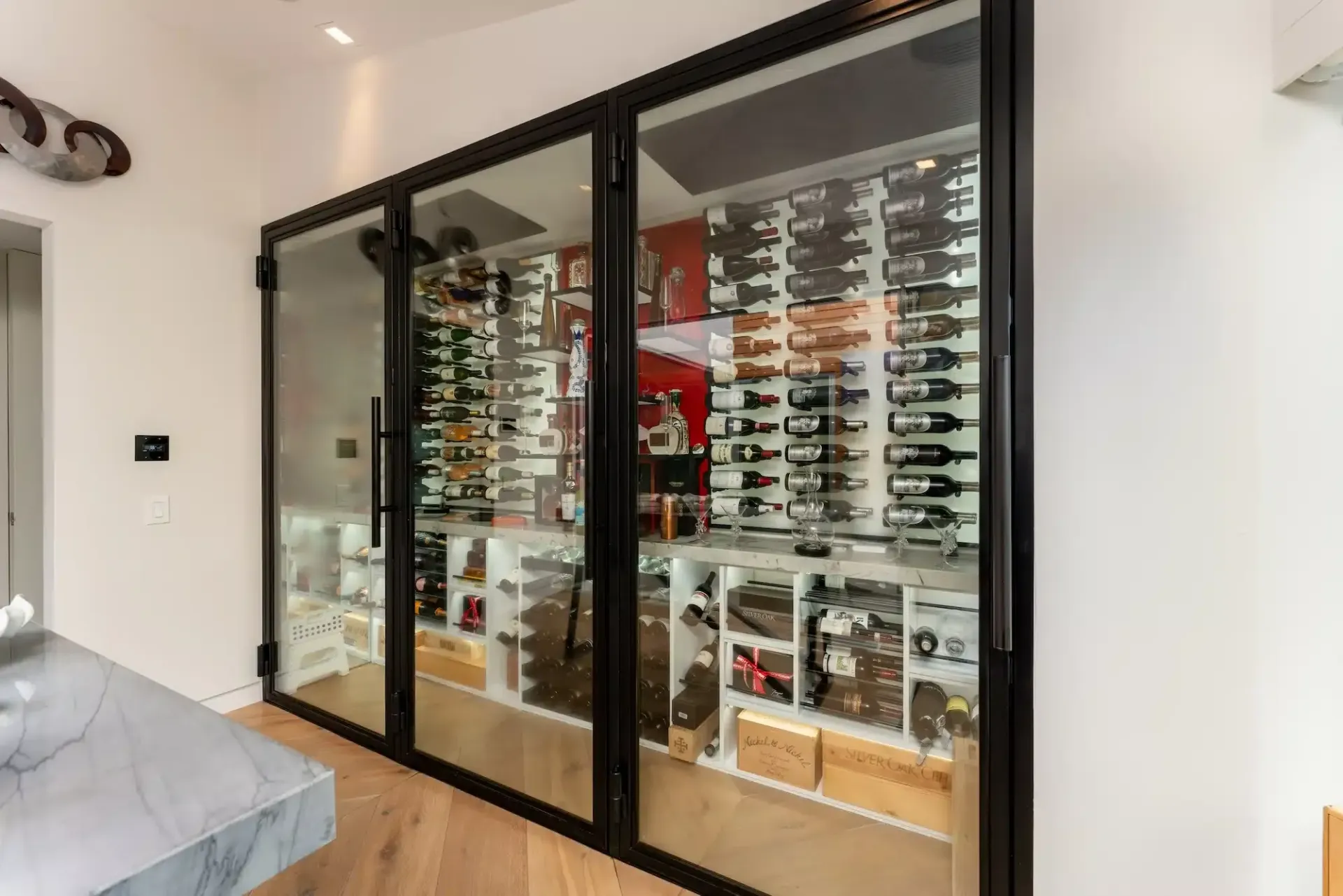 Glass-fronted shoe display cabinet in a modern room with framed sneakers and shoes inside.