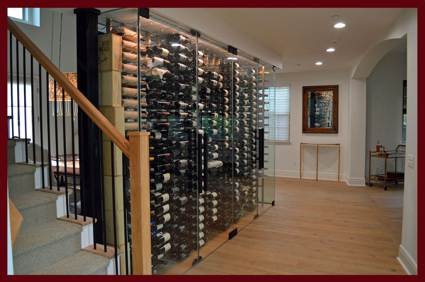 Frameless glass wine cellar door enclosing a full-height rack wall off a hallway