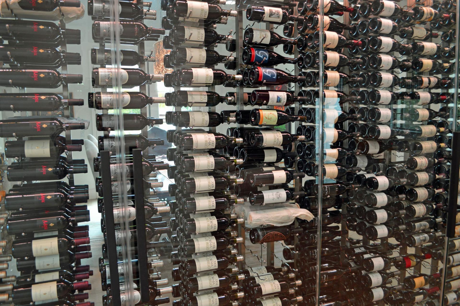 Rows of wine bottles stored horizontally on tall racks in a cellar or shop.