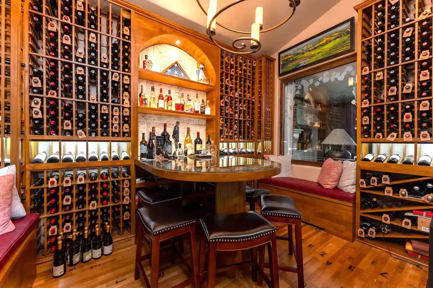 Cozy wine cellar with wall-to-wall racks, wooden table, chairs, and a bottle display on shelves