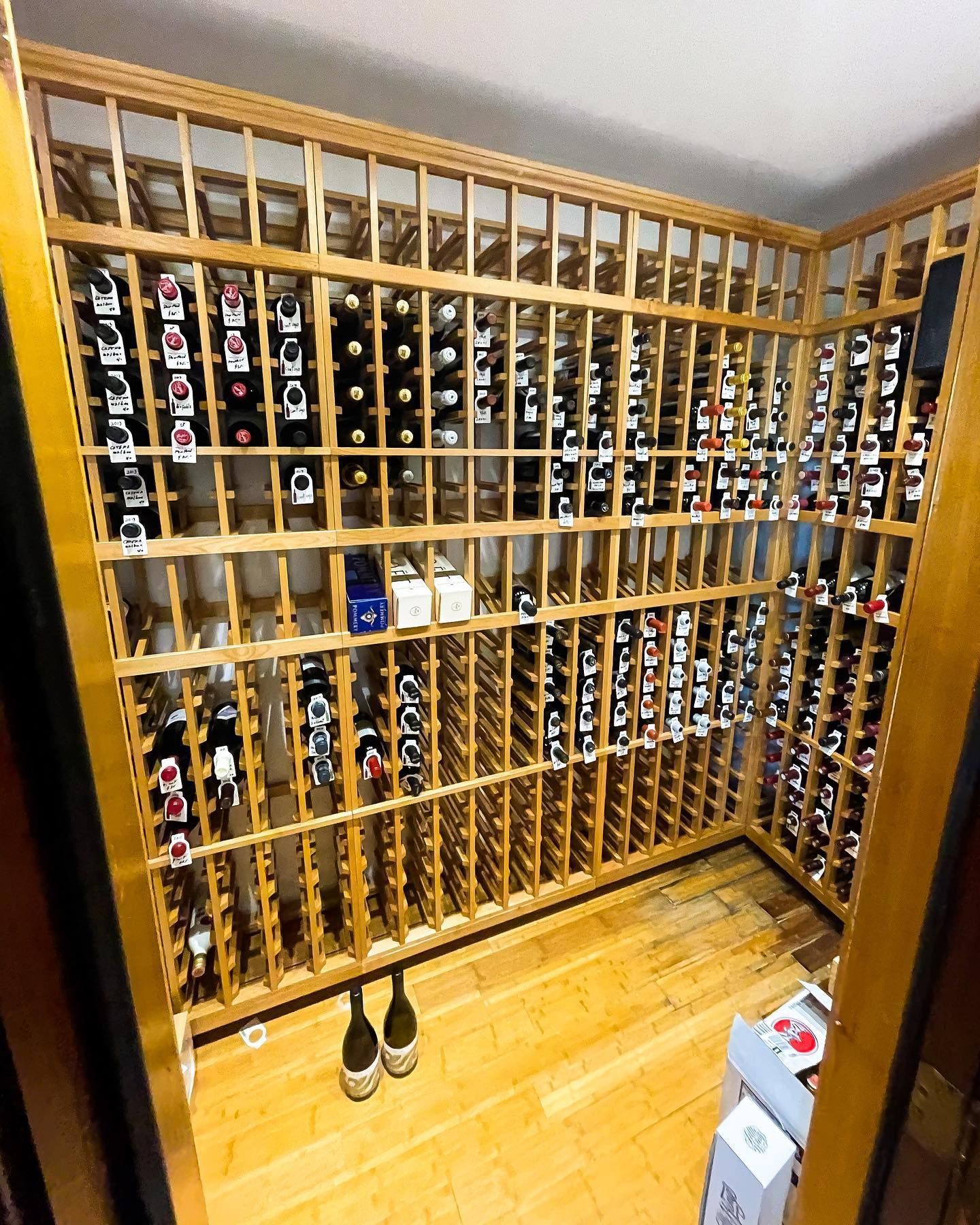 Wooden wine cellar racks filled with bottles, with a pair of shoes on the floor.