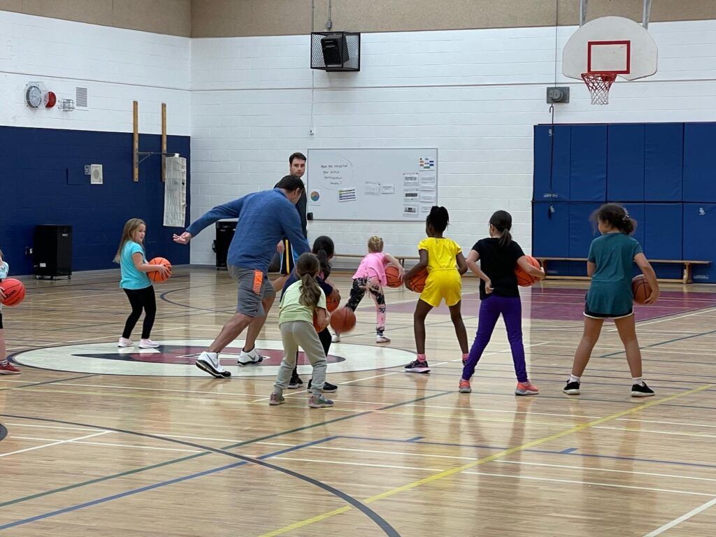 Children stretching with an instructor in a school gym during a group exercise class
