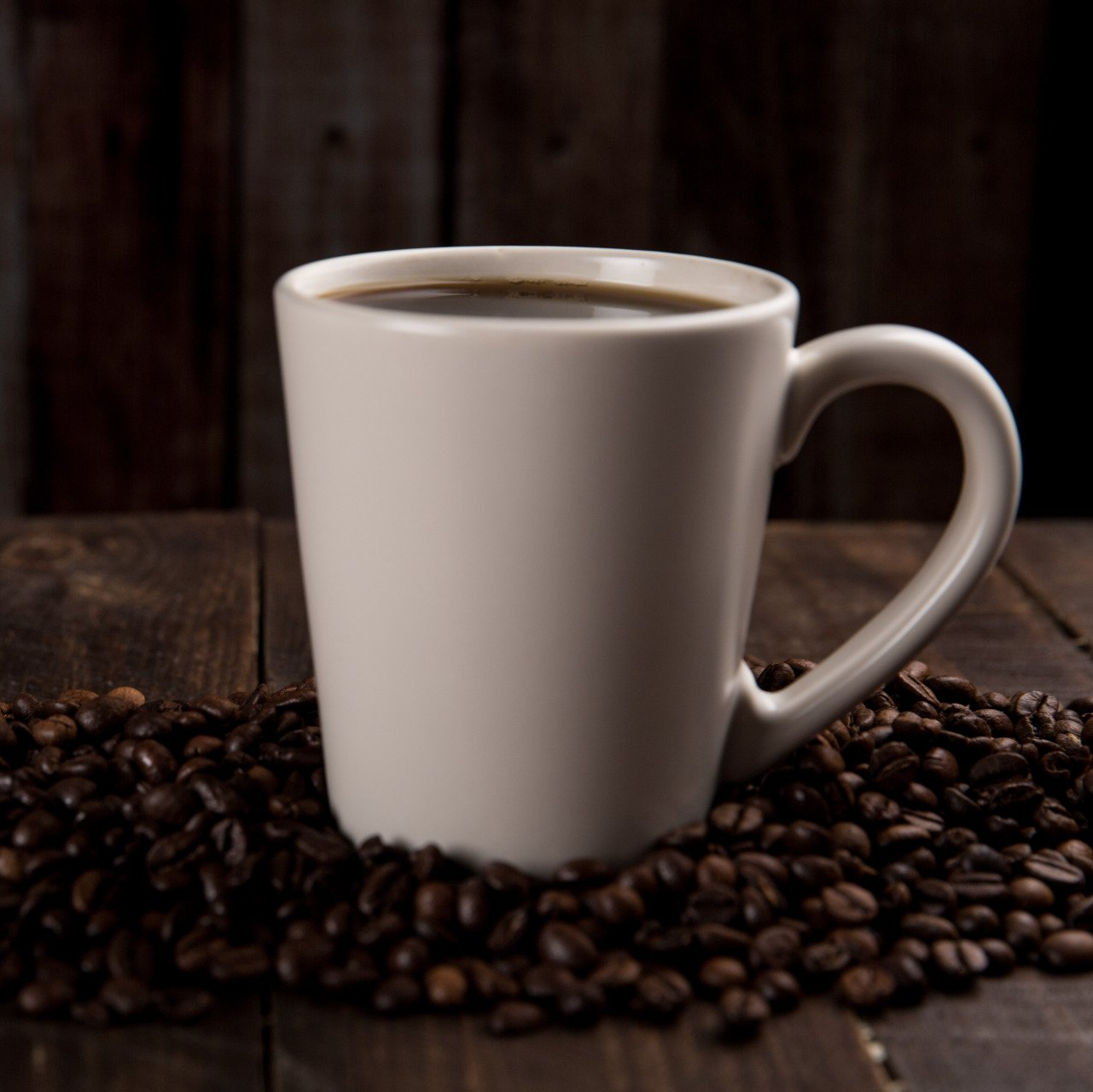 a cup of coffee sitting on top of a pile of coffee beans