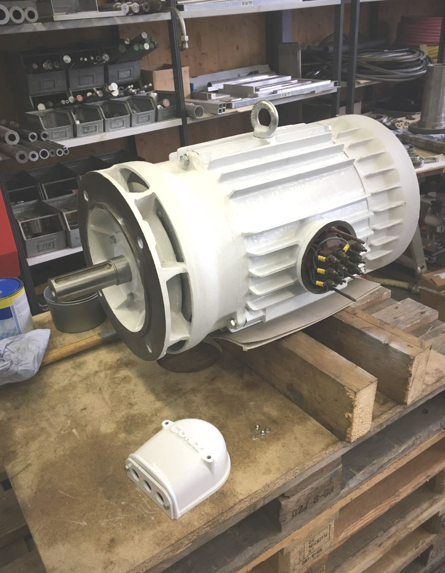 Ein großer weißer Elektromotor steht auf einem Holztisch.