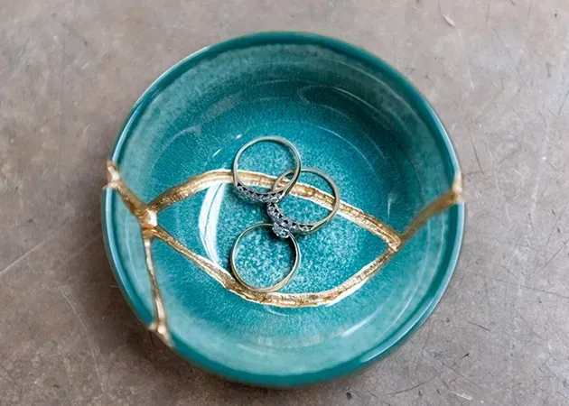 Turquoise ceramic bowl with a gold wire eye design and three small rings inside