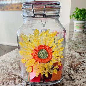 Glass jar with a painted yellow sunflower on a kitchen counter