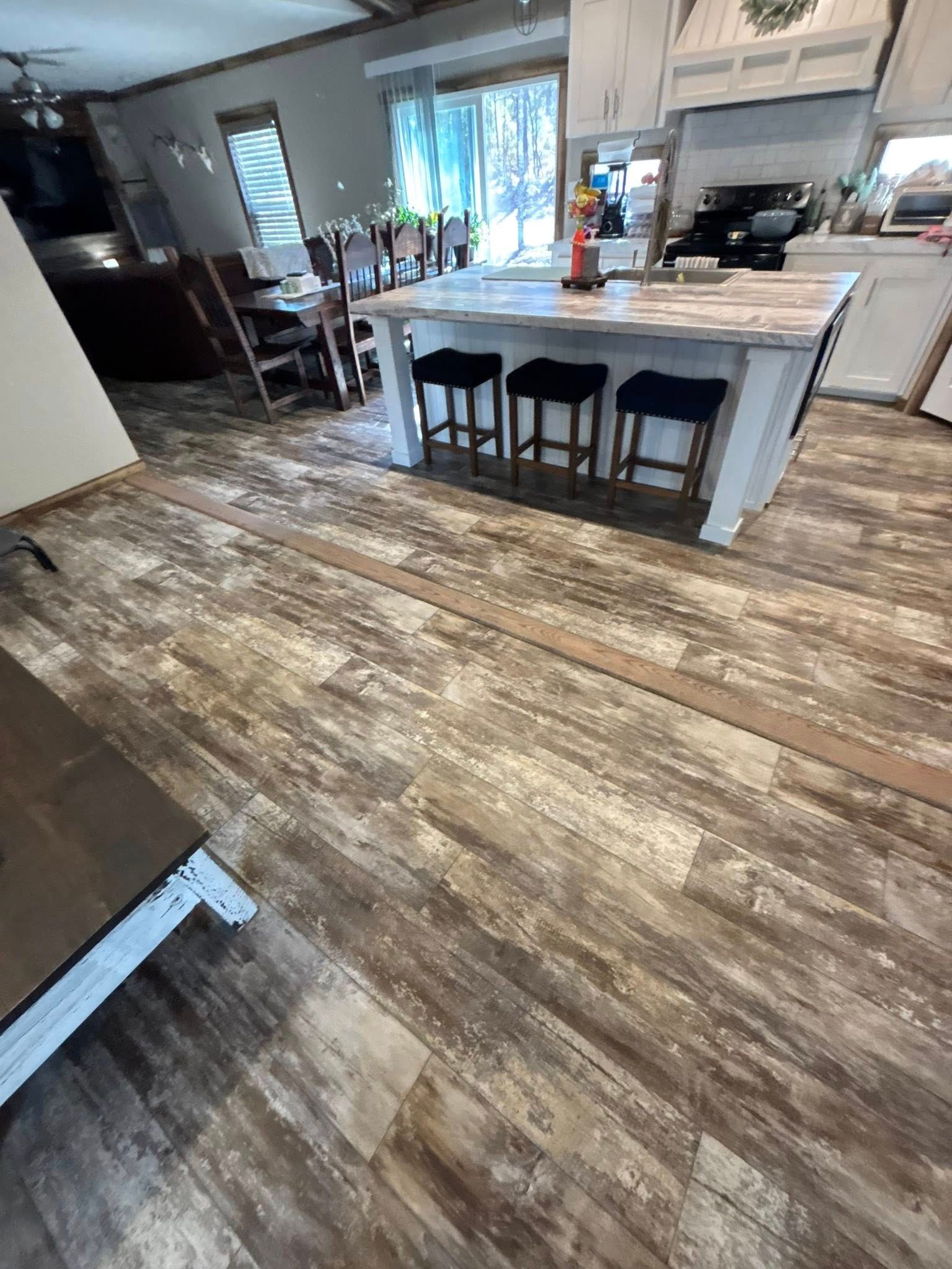 Modern kitchen with large island, bar stools, and rustic wood flooring