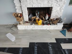 Messy fireplace with tools and debris on a light wood floor in an unfinished room
