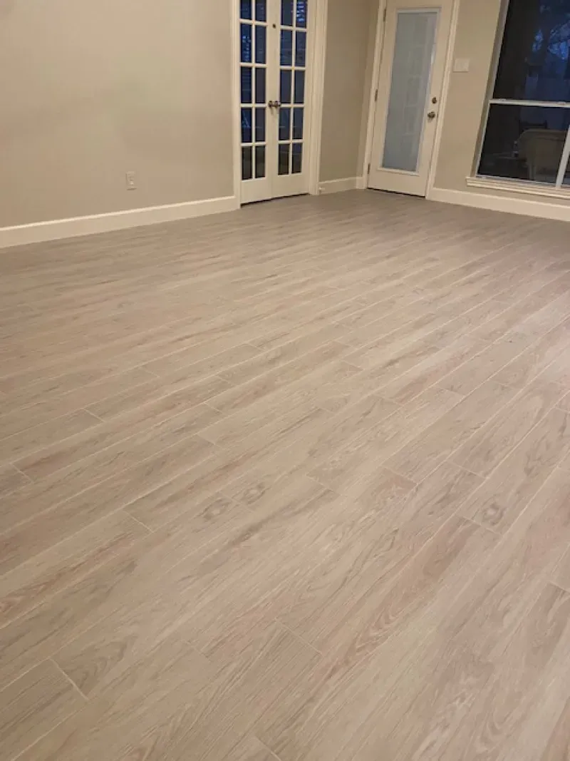 Empty light wood-floored room with white walls and glass doors.