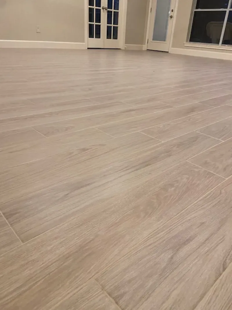 Empty room with light wood flooring and white walls, viewed from a low angle.
