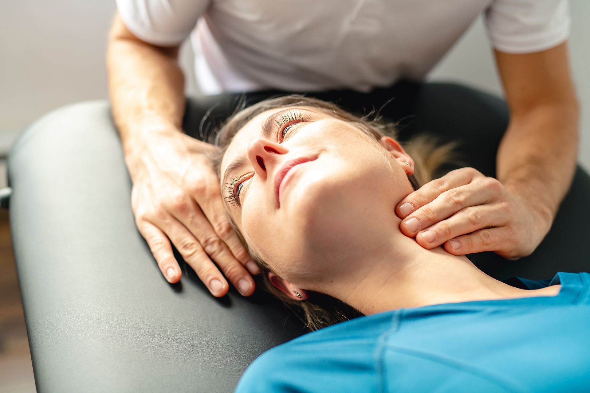 Person receiving a neck massage on a treatment table from a therapist
