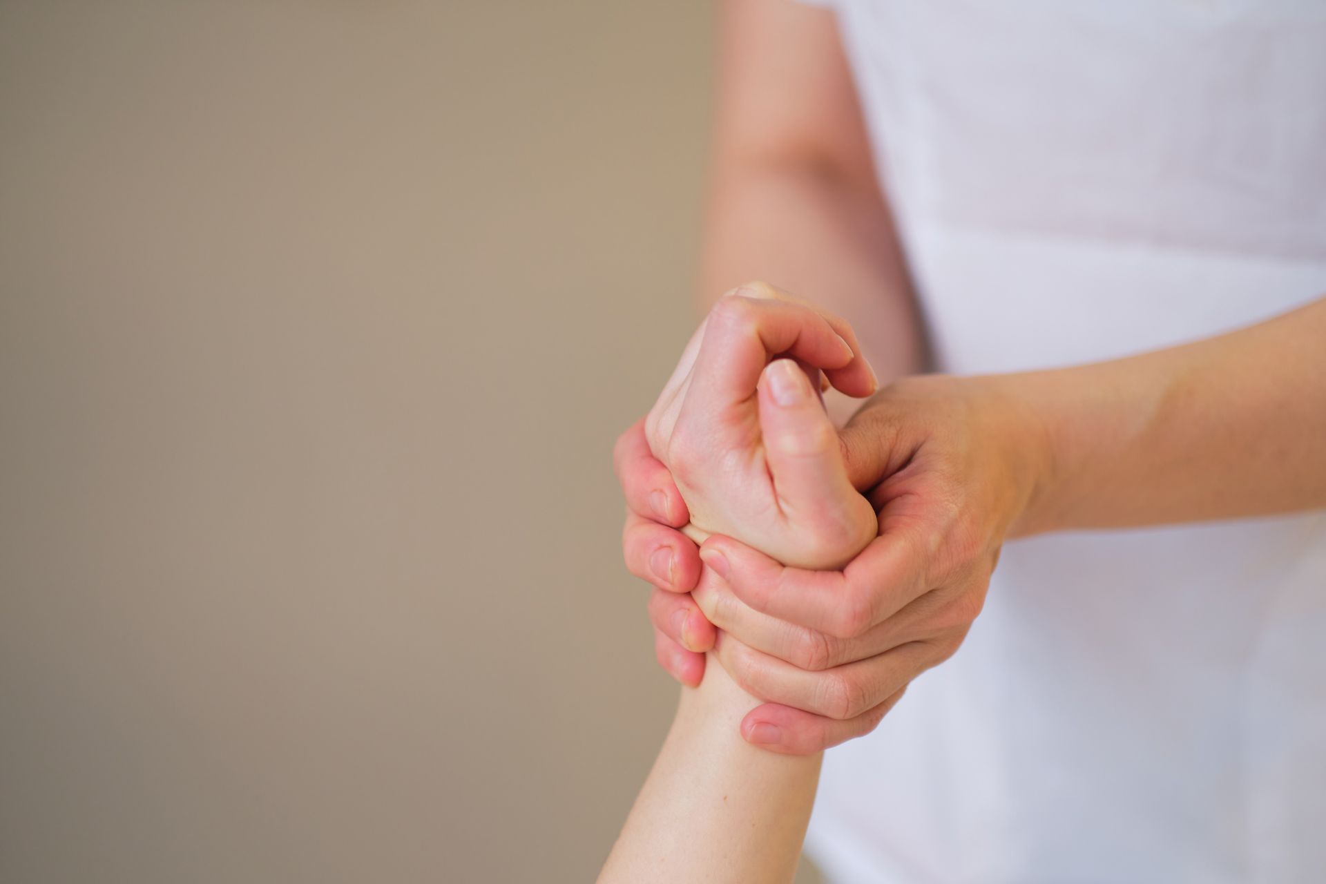 Hands holding a wrist in a neutral indoor setting
