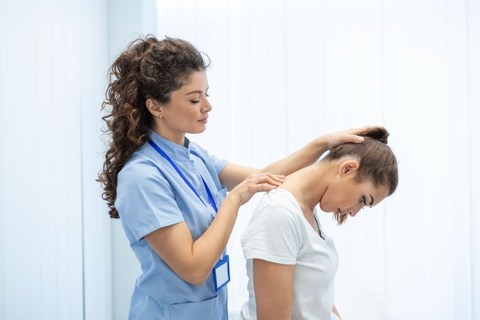 Physiotherapist massaging a patient’s neck and shoulders in a bright clinic setting