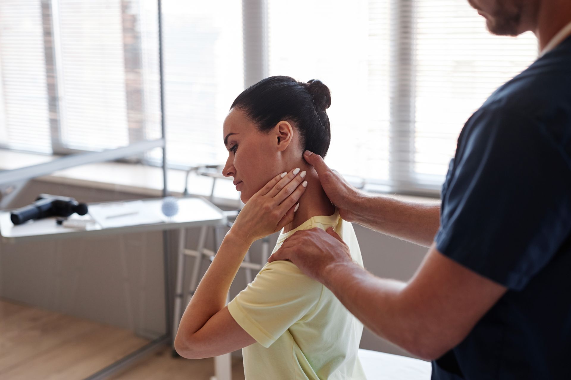 Physical therapist massaging a woman’s neck in a bright clinic room
