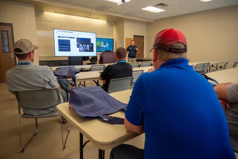 Classroom presentation with a speaker, slides on screen, and seated attendees.