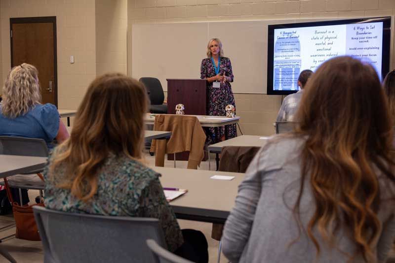 Woman giving a presentation in a classroom setting.
