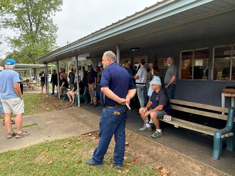Group of people standing outside a building with a covered porch.