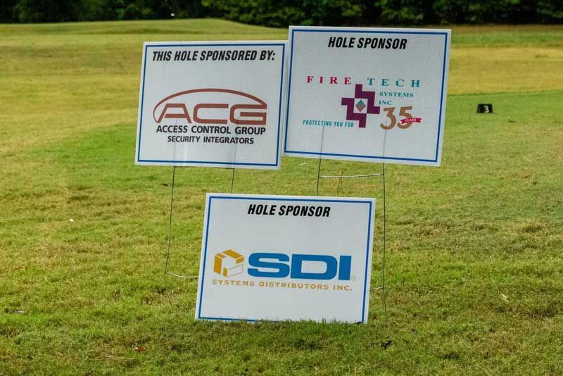 Three sponsor signs on a green golf course.