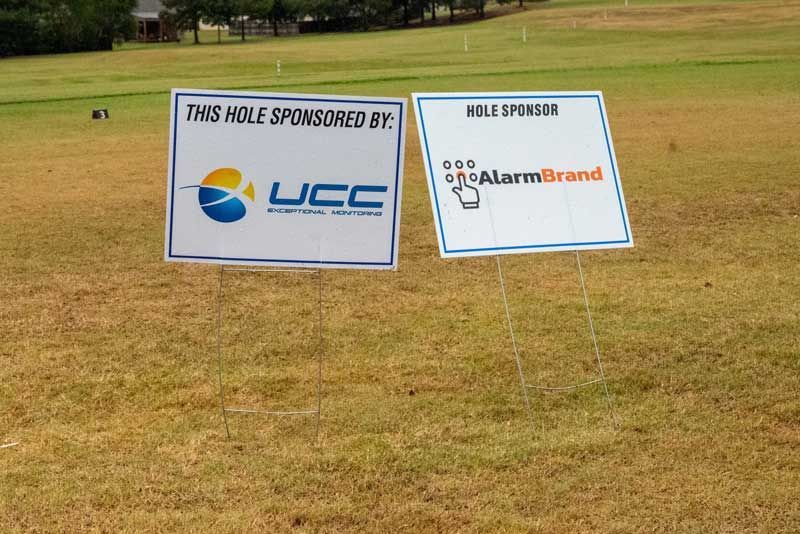 Two hole sponsor signs on a golf course. 