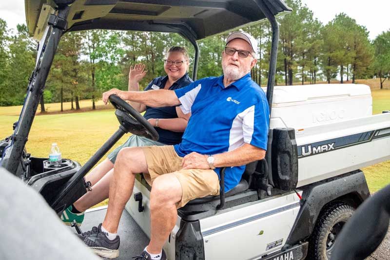 Two people in a golf cart.
