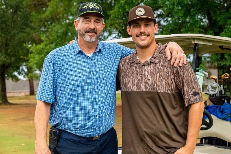 Two men standing on a golf course.