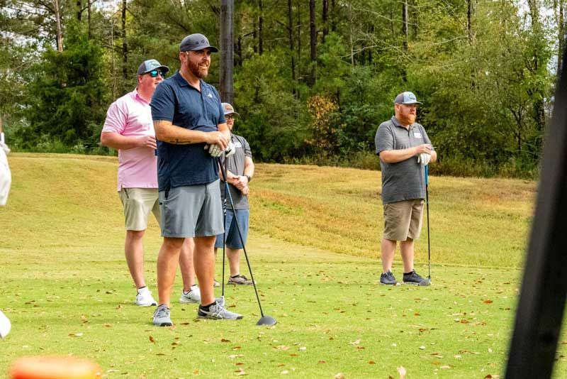 Golfers standing on a green, holding clubs.