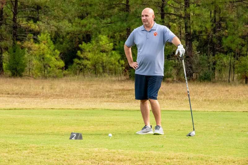 Man on a golf course stands with a club.
