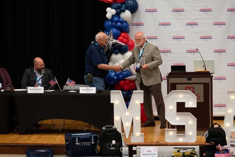 Two men shaking hands on stage with 