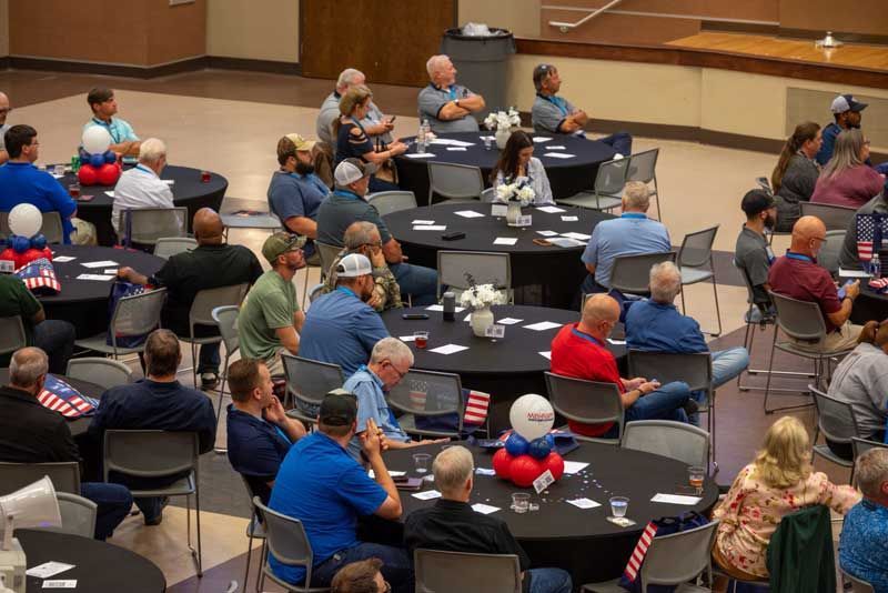 People seated at round tables in a large room.
