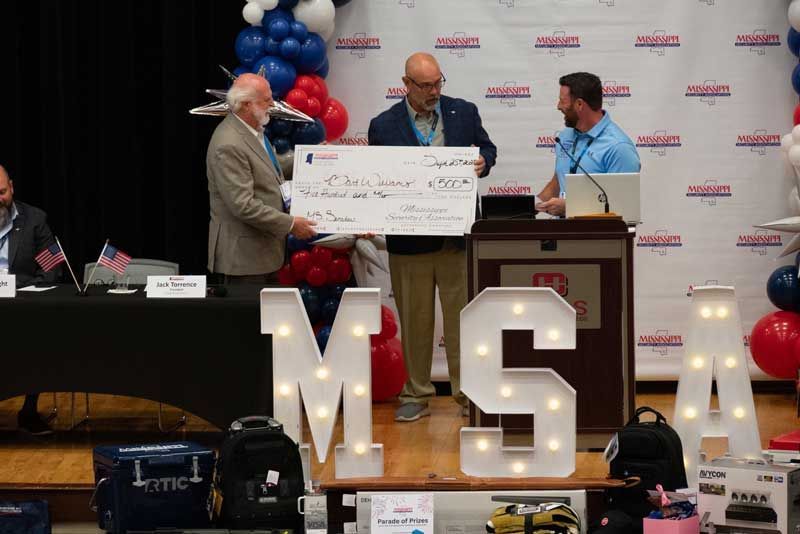 Men present a large check at an event.