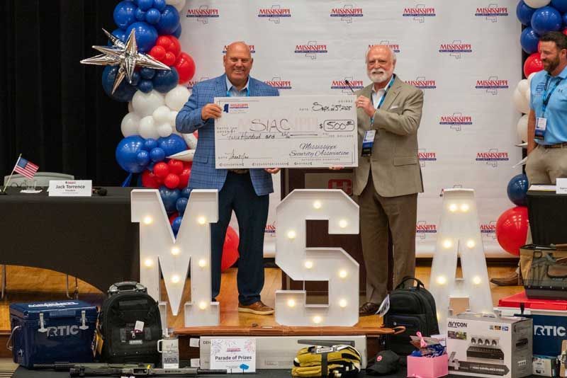 Two men hold a large check.