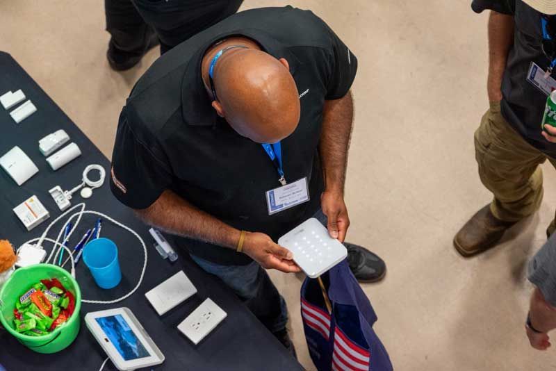 Man examines a white, gridded object at a table with other items.