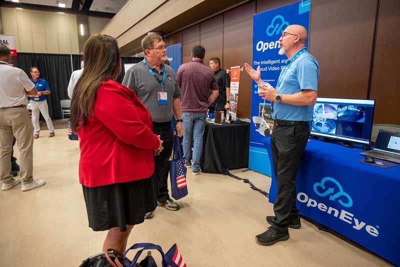 People at a trade show booth with OpenEye logo. 