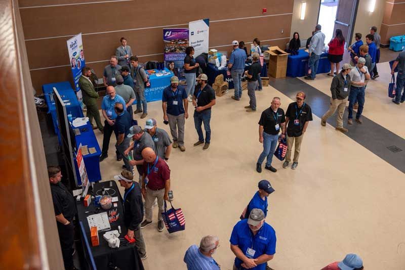 Large room with people at booths, likely a trade show. 