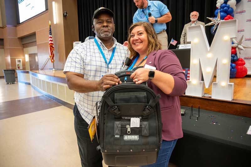 Man and woman holding a black backpack.