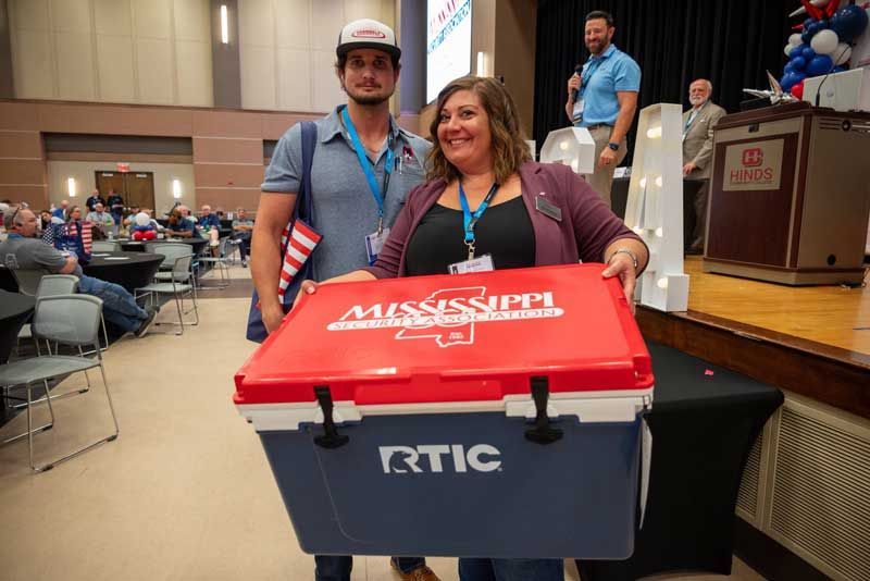 Two people holding a large cooler.