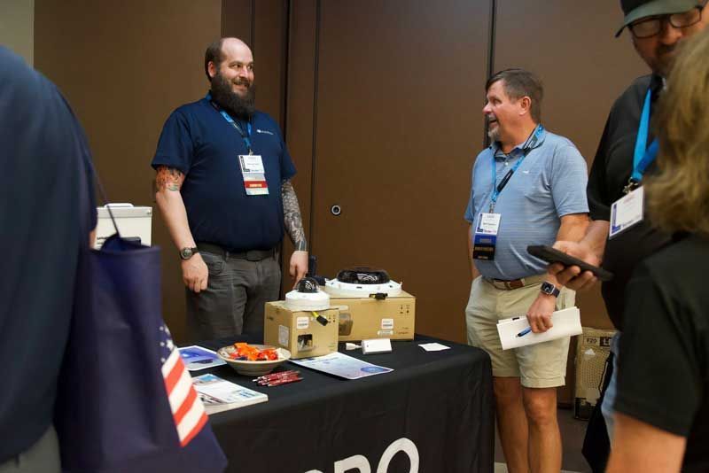 Men at a trade show booth, talking. 