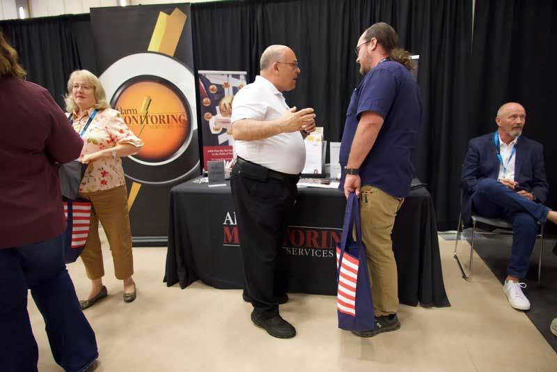 People at a booth with a sign.