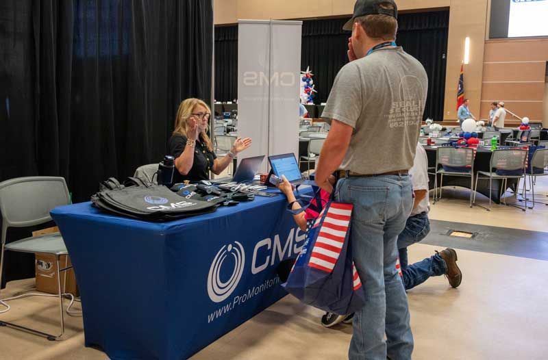 Woman at a booth, speaking to a man standing nearby. 