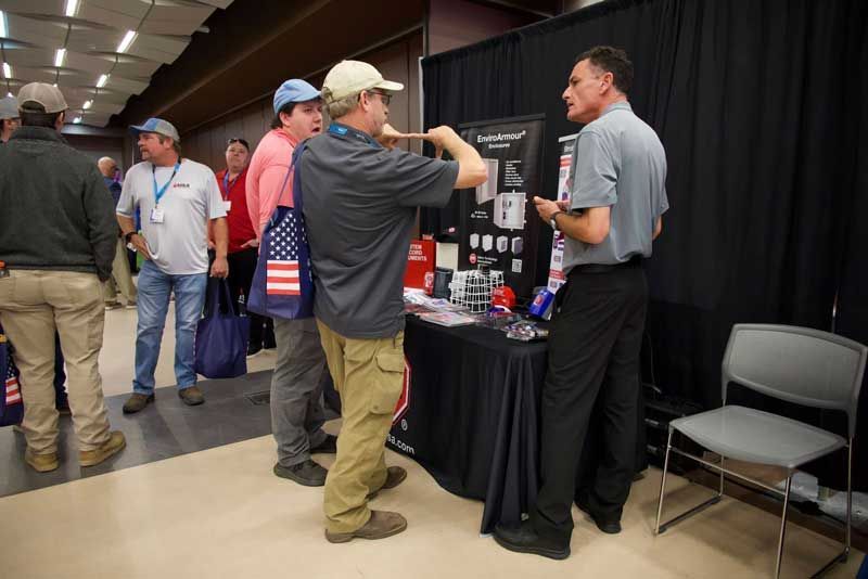 People at a trade show booth, discussing product information. 