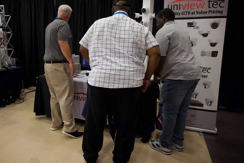 Three people looking at a display table with security camera information.