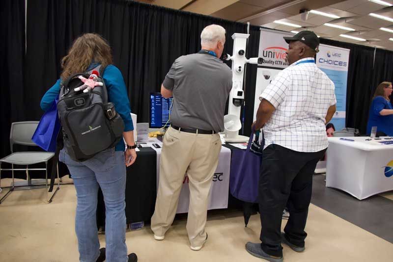 People at a vendor booth with product displays and information table.