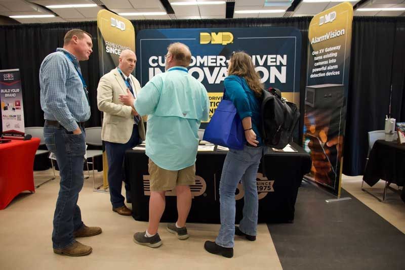 People at a trade show booth with the sign.